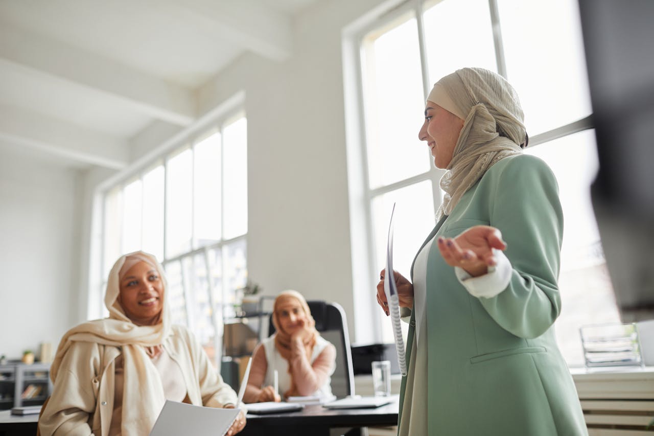 Women in hijabs having a professional discussion at a bright office space.